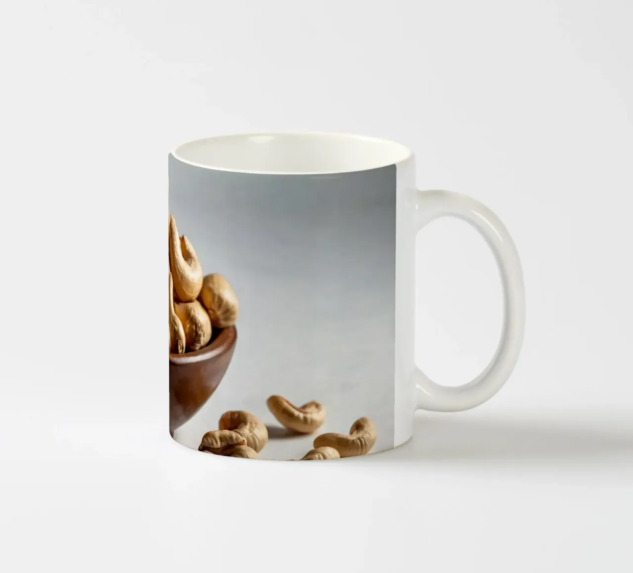 Anacardi crudi disposti su una superficie bianca per uno spuntino sano tazza in ceramica da DesignDoodle