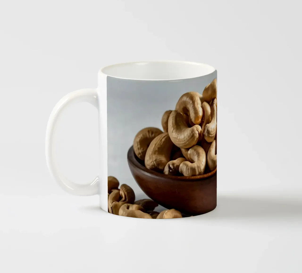 Anacardi crudi disposti su una superficie bianca per uno spuntino sano tazza in ceramica da DesignDoodle