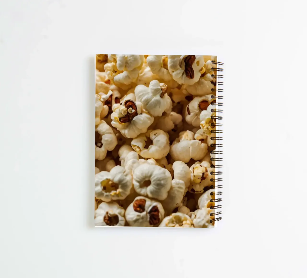Plain popcorn kernels scattered in a bowl, ready for snackin spiral notebook by DesignDoodle