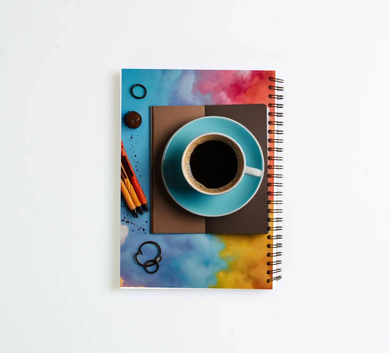 workspace featuring a blue cup of coffee on a colorful art spiral notebook by DesignDoodle