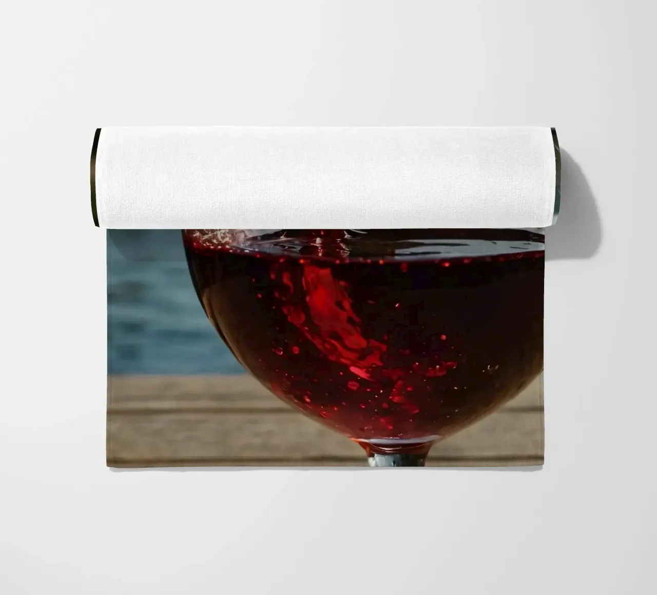 Versare del vino rosso in un bicchiere accanto a un lago tranquillo, al sole. telo mare da DesignDoodle