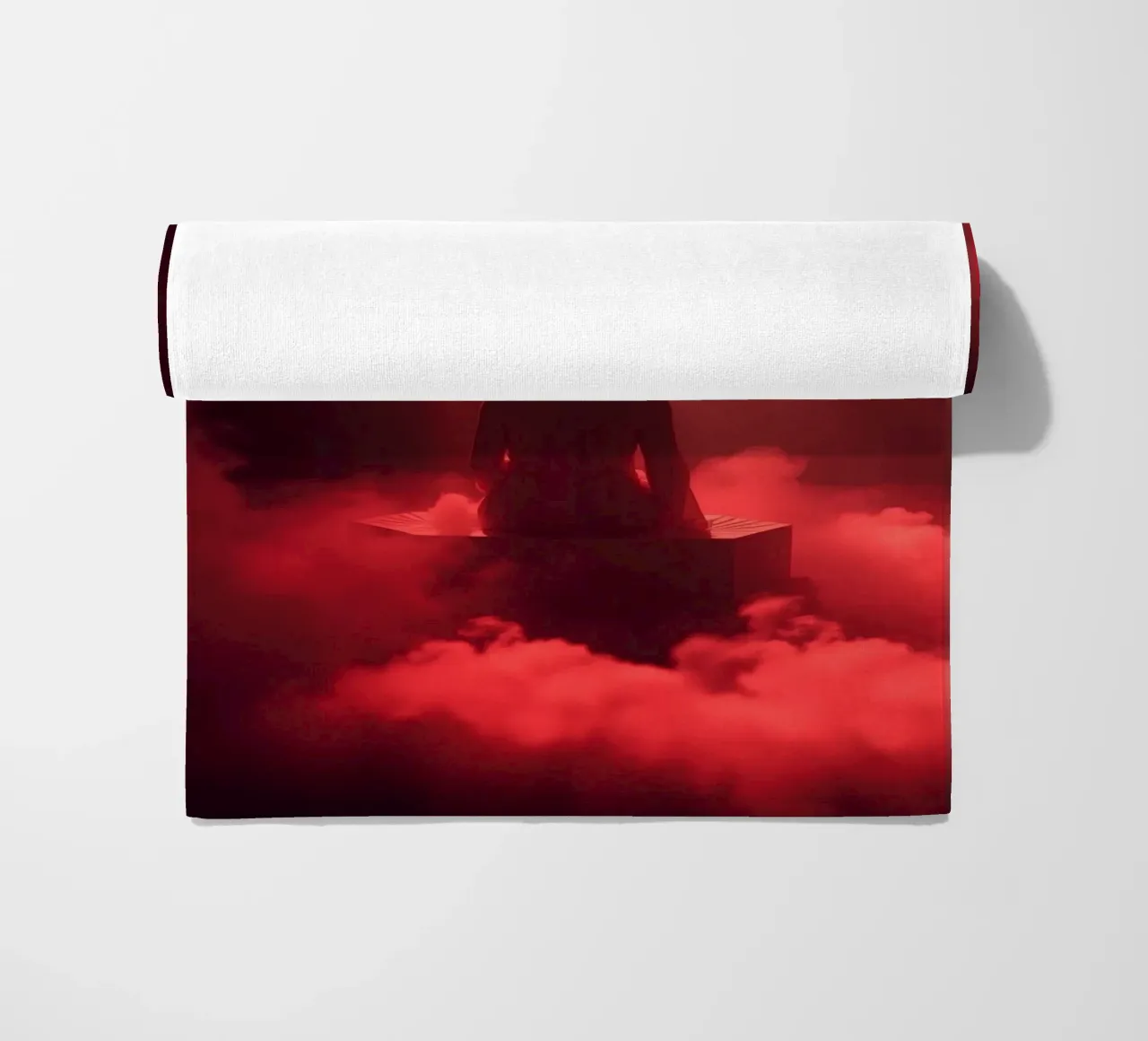 Captivating red light envelops a man sitting on a box in fog beach towel by DesignDoodle