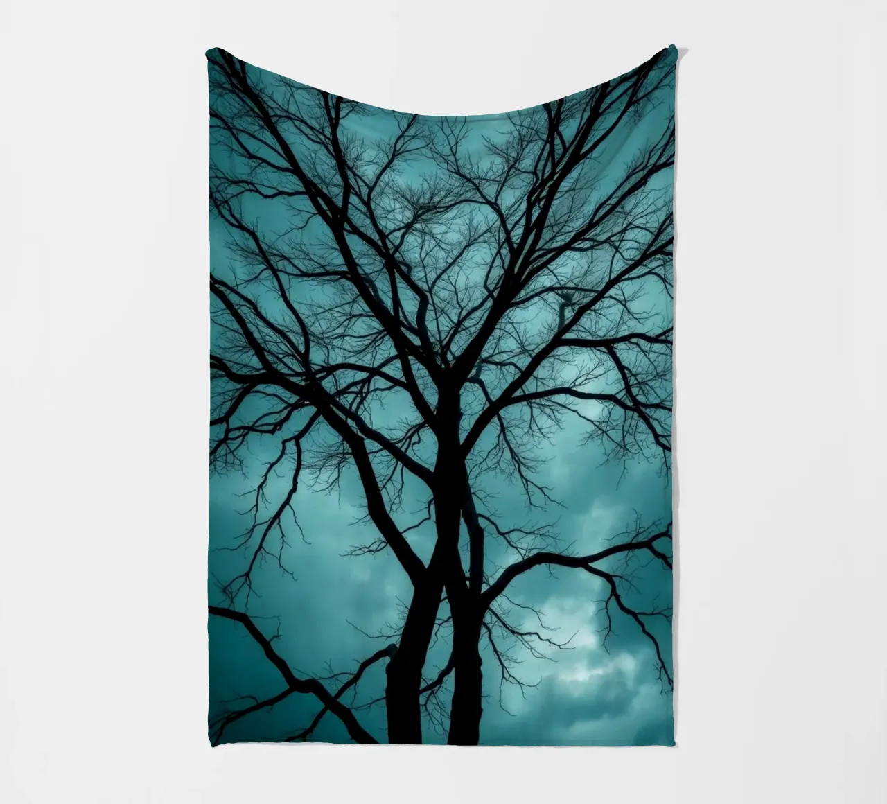 Dark silhouette of a leafless tree against a stormy sky fleece blanket by DesignDoodle