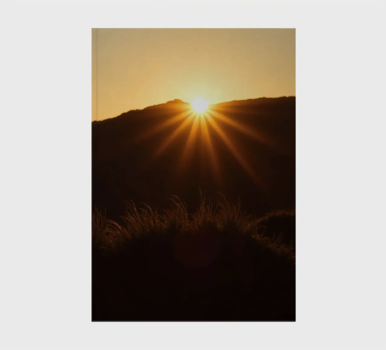 Vibrant sunset casting rays over hillside notebook by DesignDoodle