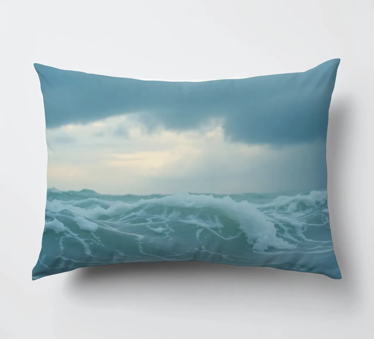 Le onde si infrangono sulla riva sotto le nuvole scure del crepuscolo cuscino da DesignDoodle