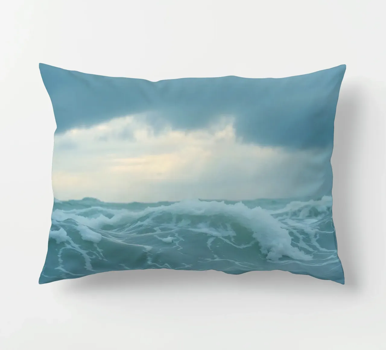 Le onde si infrangono sulla riva sotto le nuvole scure del crepuscolo cuscino da DesignDoodle