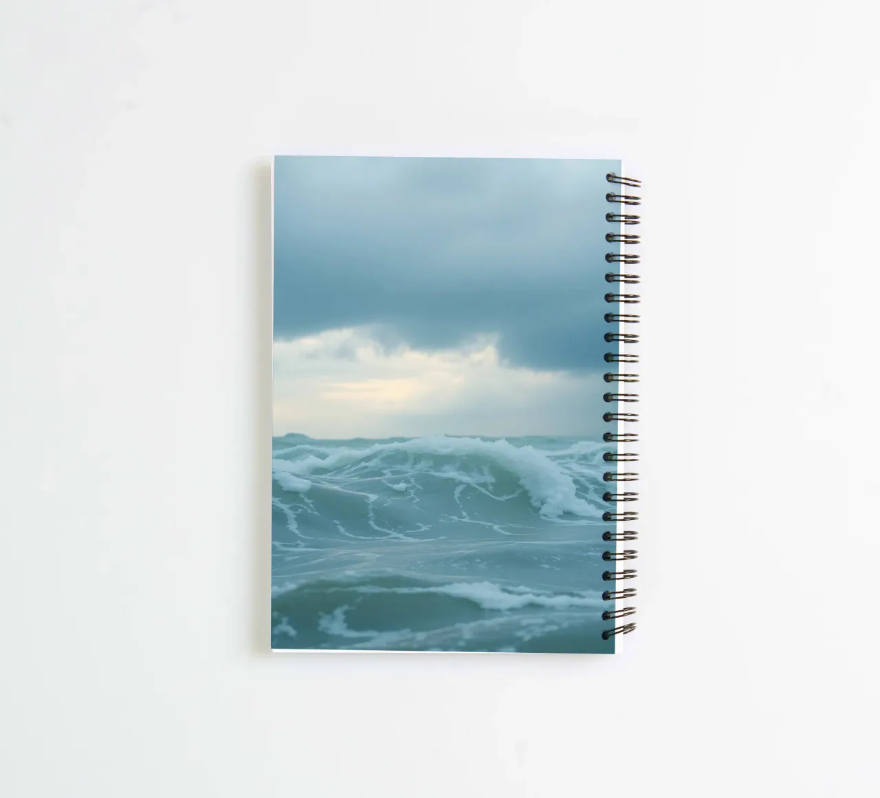 Waves crash against the shore under dark clouds at twilight spiral notebook by DesignDoodle