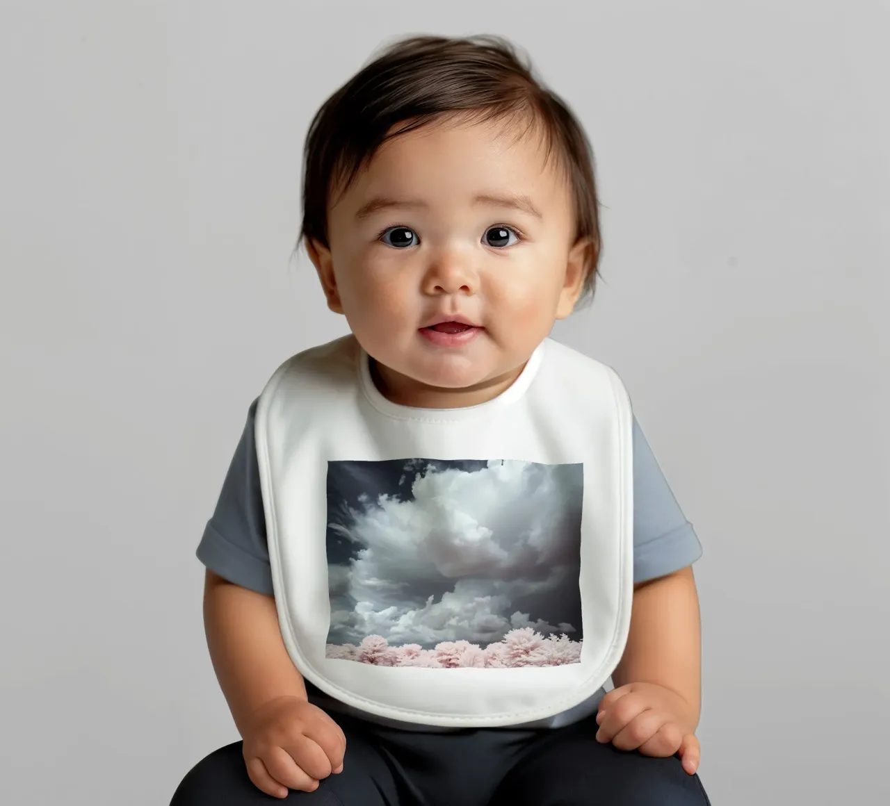 Dramatic clouds hover over pink-tinted trees in an enchantin baby bib by DesignDoodle