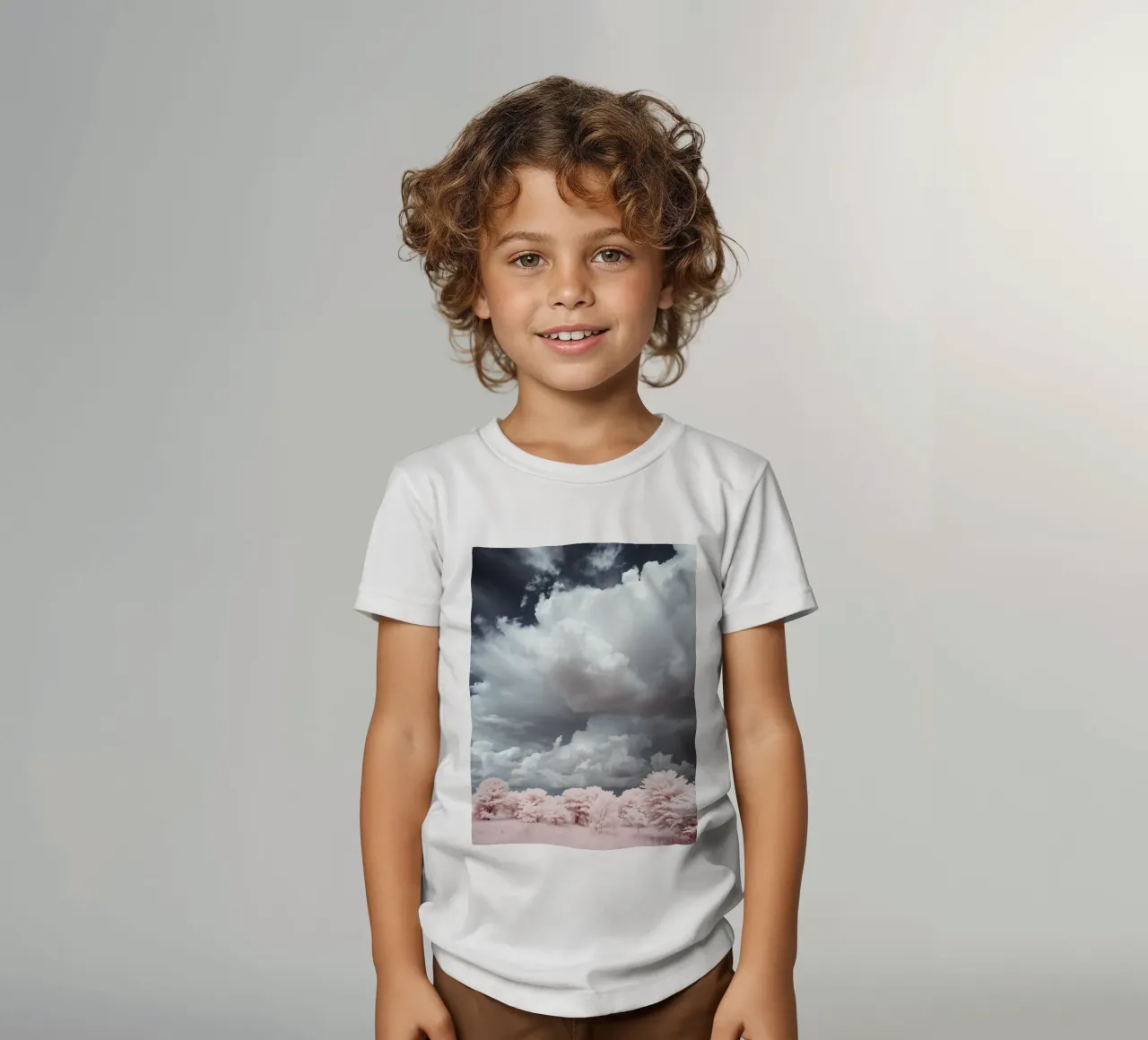 Dramatic clouds hover over pink-tinted trees in an enchantin kids t-shirt by DesignDoodle