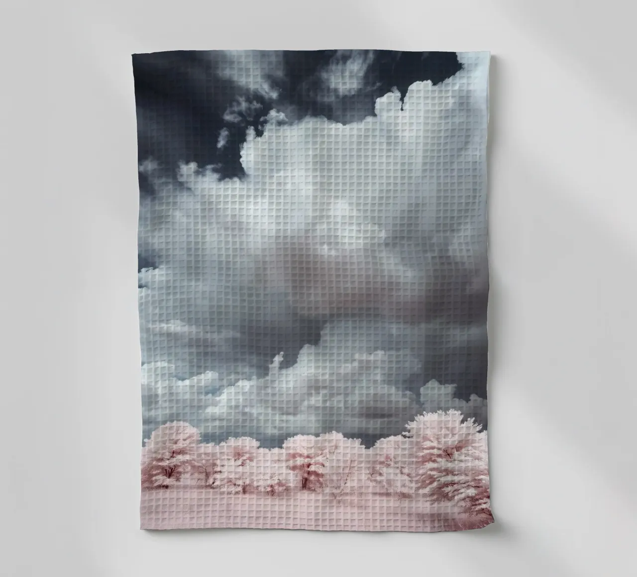 Dramatic clouds hover over pink-tinted trees in an enchantin tea towel by DesignDoodle