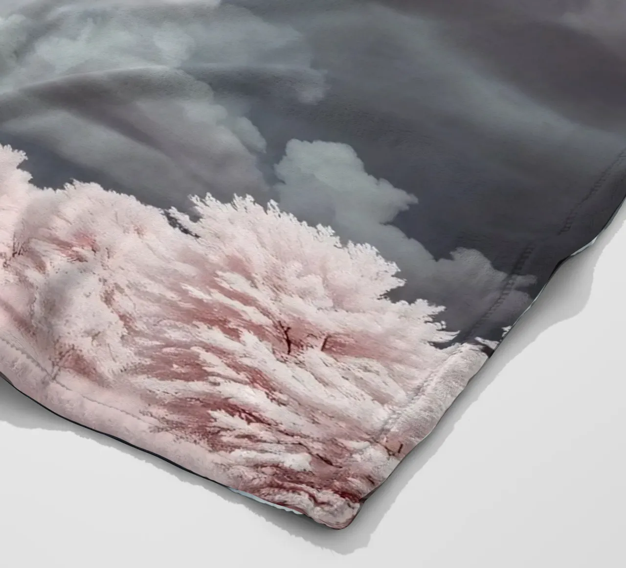 Dramatic clouds hover over pink-tinted trees in an enchantin fleece blanket by DesignDoodle