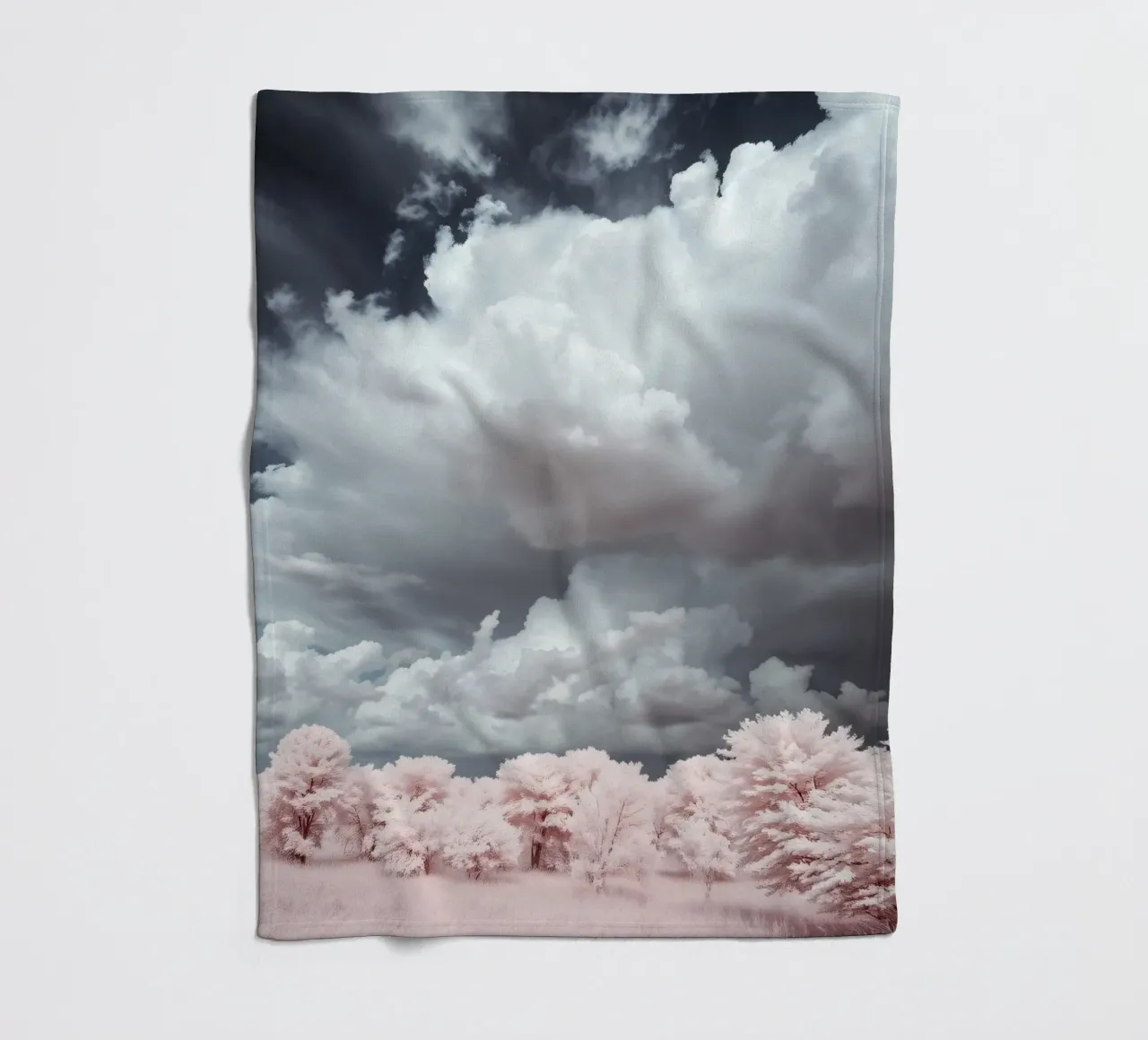 Dramatic clouds hover over pink-tinted trees in an enchantin fleece blanket by DesignDoodle