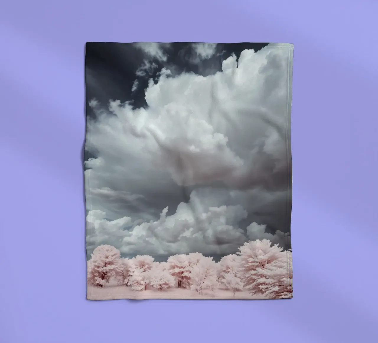 Dramatic clouds hover over pink-tinted trees in an enchantin fleece blanket by DesignDoodle
