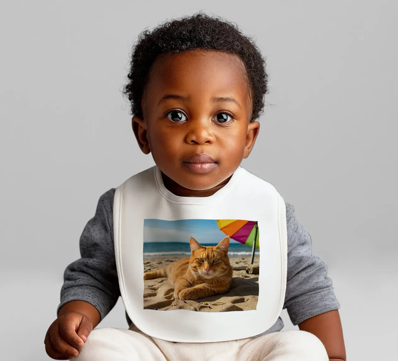 Gatto arancione che si rilassa sulla spiaggia sabbiosa sotto un ombrellone colorato bavaglino da DesignDoodle