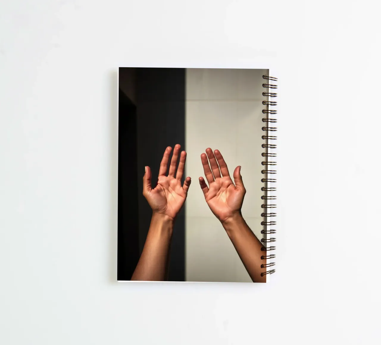 Hands reaching towards light in a minimalist setting spiral notebook by DesignDoodle