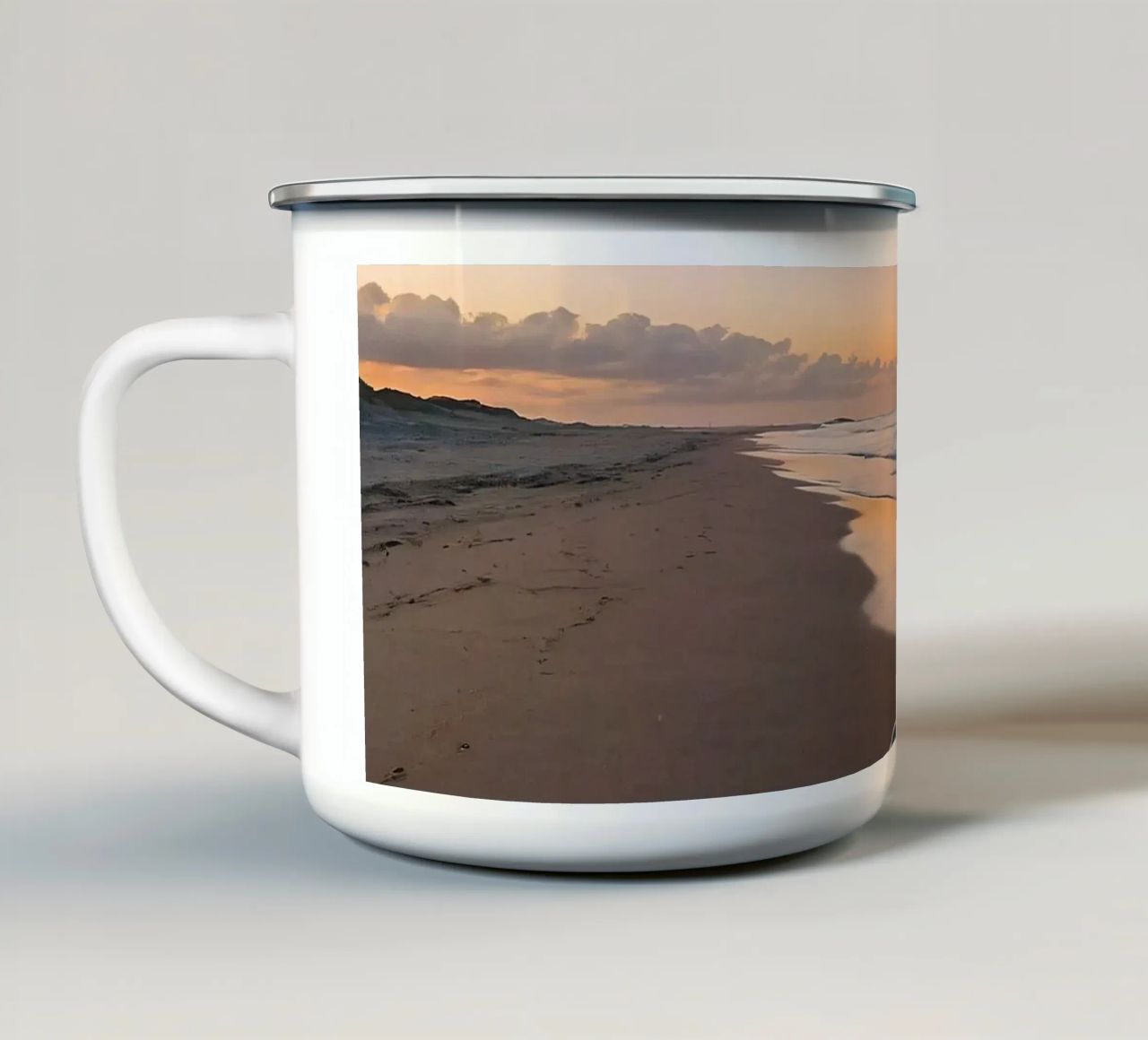 Spiaggia serena al tramonto, con le onde che lambiscono la riva. tazza in smalto da DesignDoodle