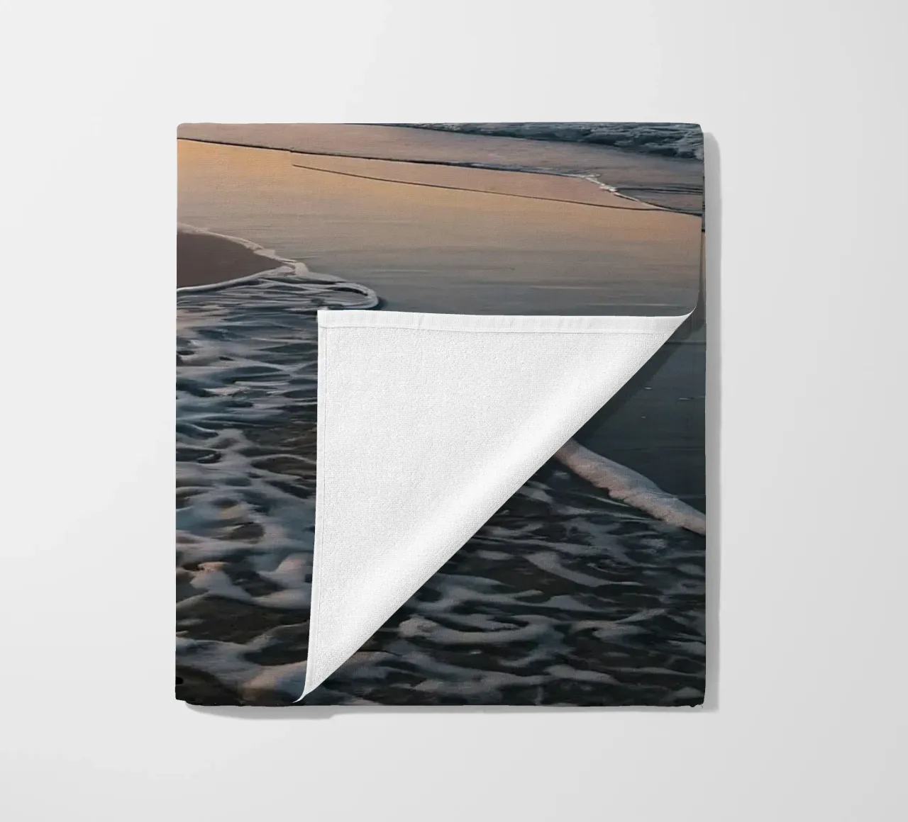 Serene beach at sunset with gentle waves lapping at the shor beach towel by DesignDoodle