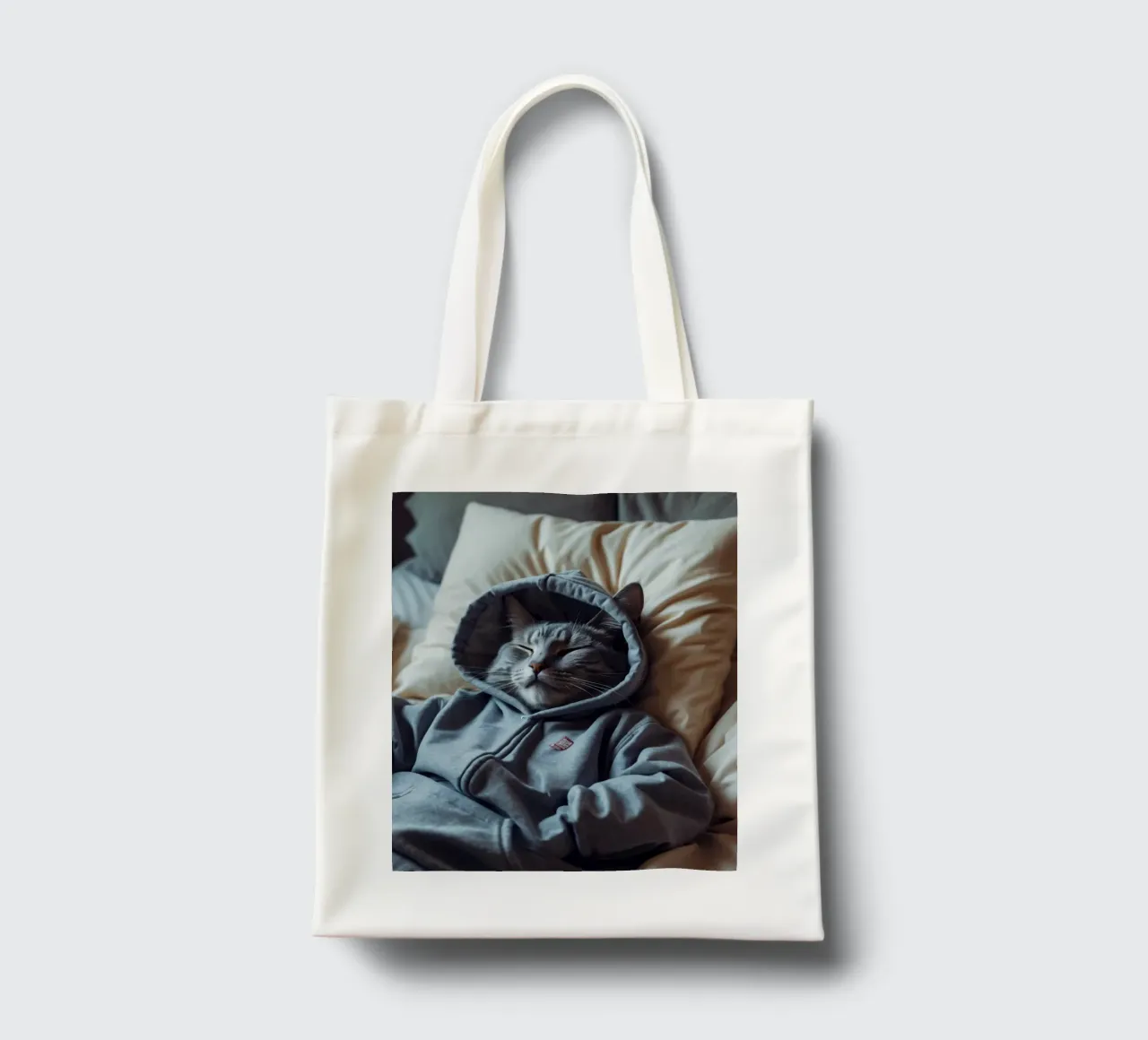 Gato descansando cómodamente en una sudadera con capucha sobre una suave almohada tote bag de DesignDoodle
