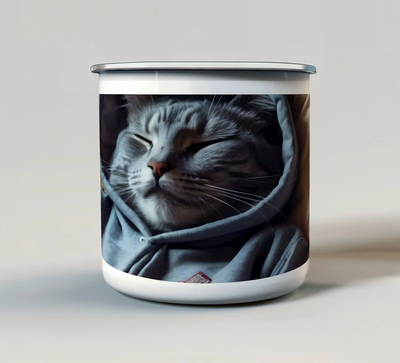 Gatto che riposa comodamente in felpa su un morbido cuscino tazza in smalto da DesignDoodle