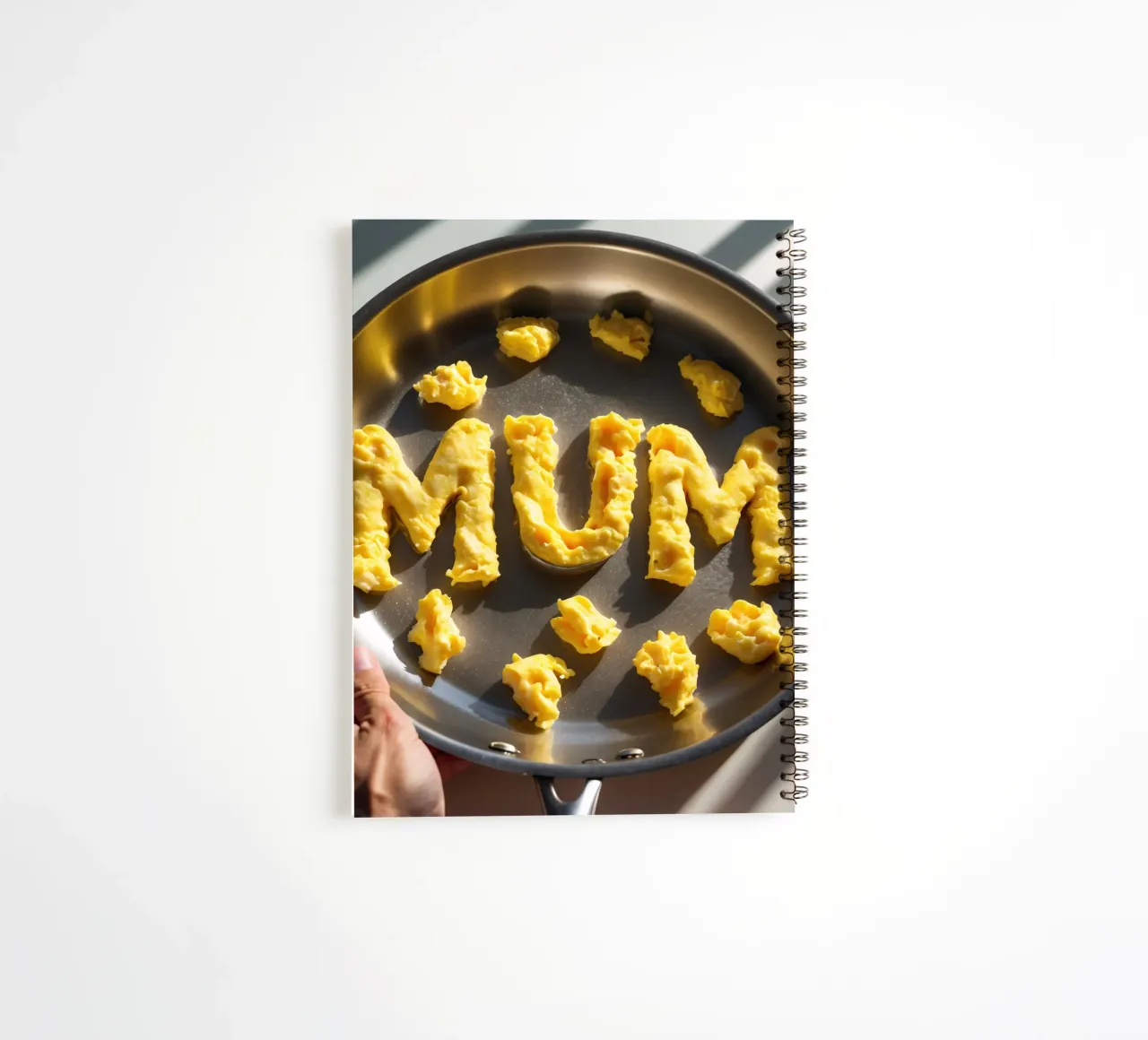 Celebrating Mum with scrambled eggs shaped into letters in a spiral notebook by DesignDoodle