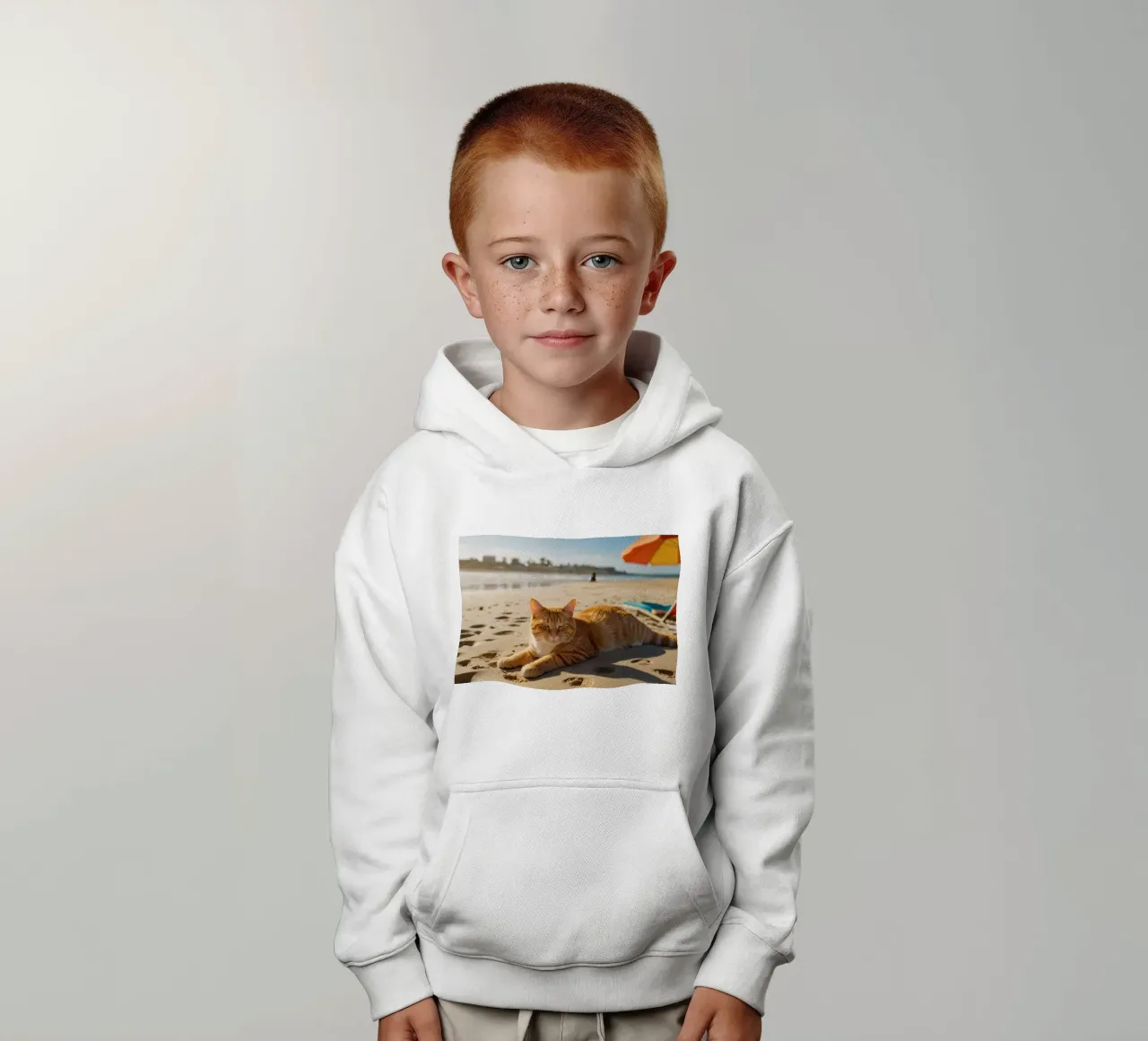 Chat orange se prélassant sur une plage ensoleillée avec un parasol sweat à capuche enfant de DesignDoodle