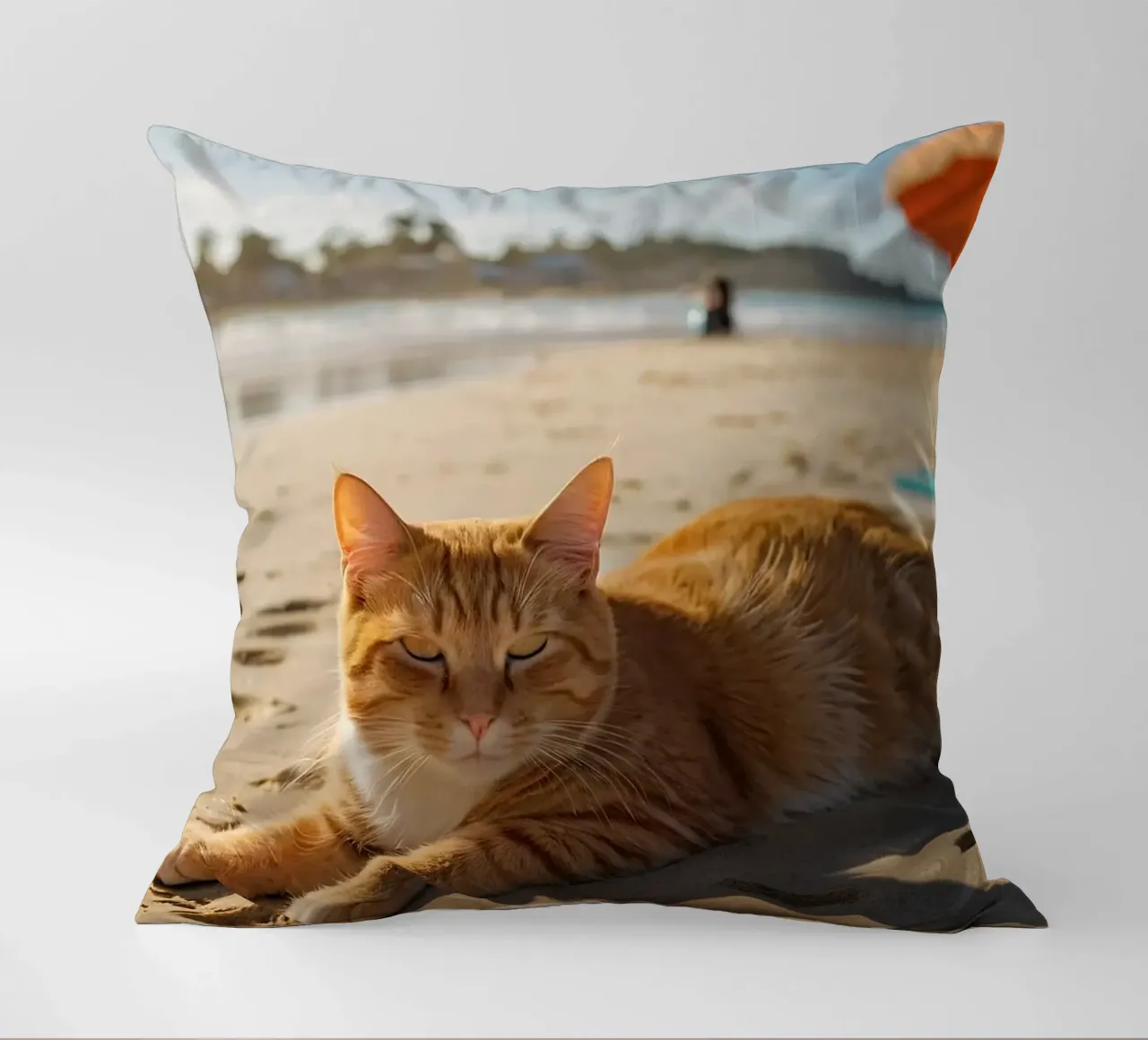 Gatto arancione che si sdraia su una spiaggia assolata con un ombrello cuscino da DesignDoodle