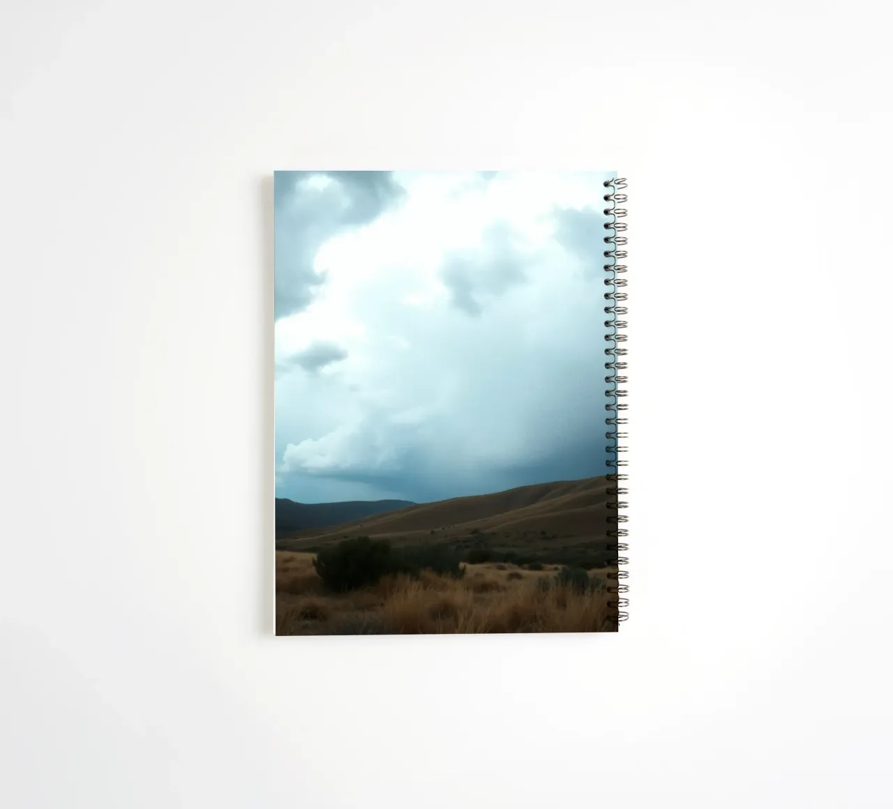 Dark storm clouds gather over a vast landscape spiral notebook by DesignDoodle