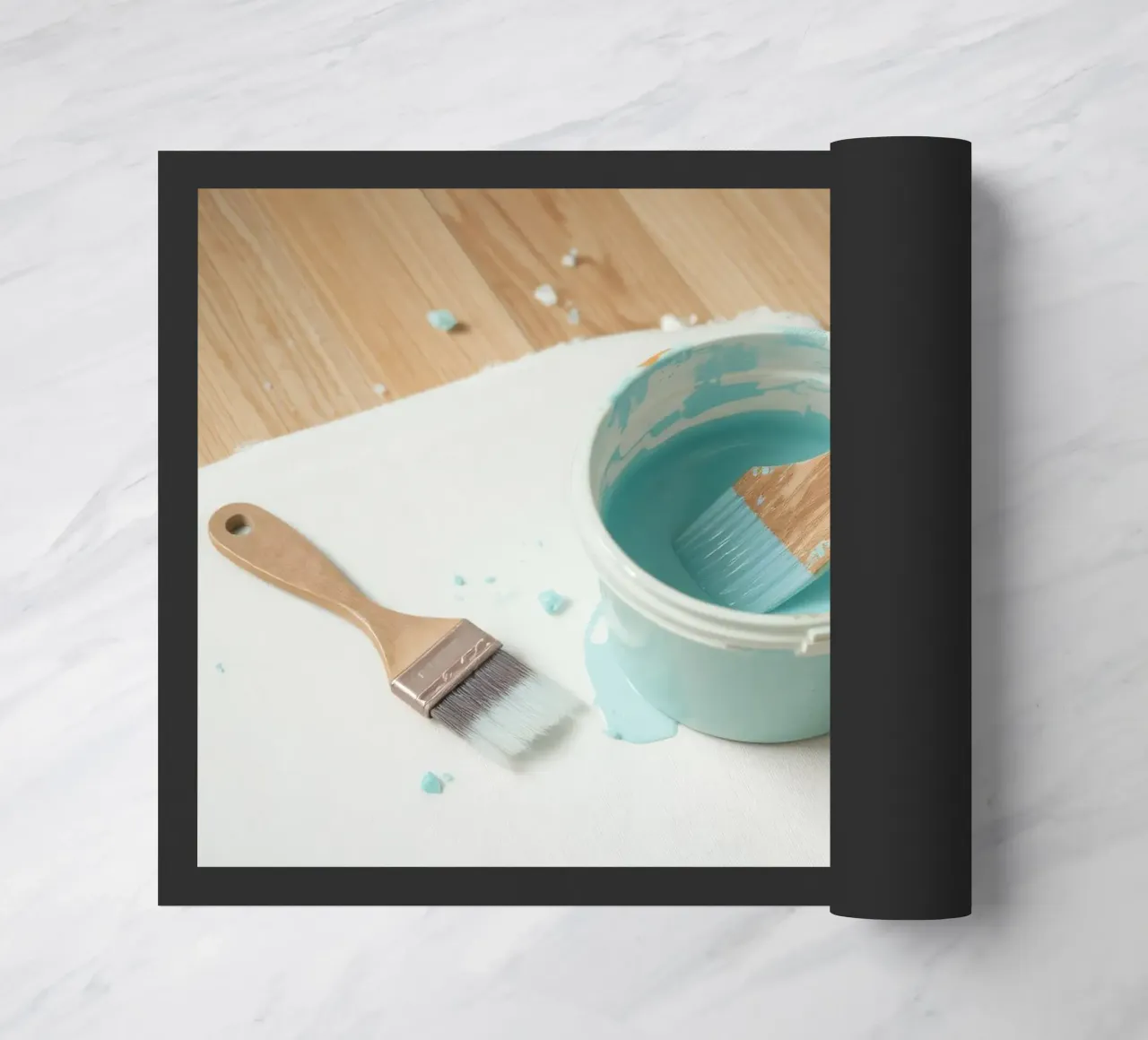 Un pincel de madera descansa en un bote de pintura azul junto a una brocha pequeña felpudo de DesignDoodle