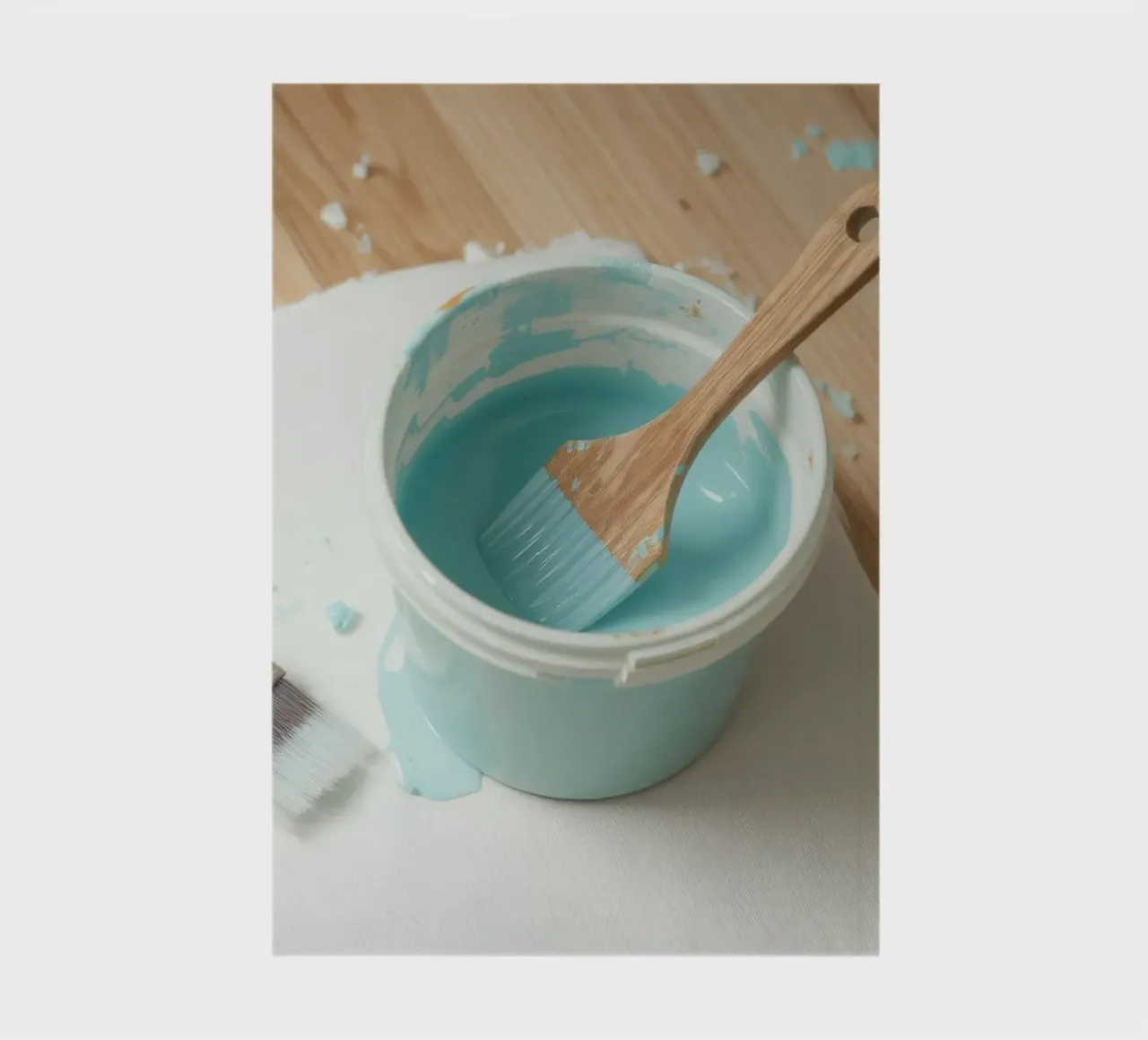 Un pinceau en bois repose dans un pot de peinture bleu à côté d'un petit pinceau. carnet de notes de DesignDoodle