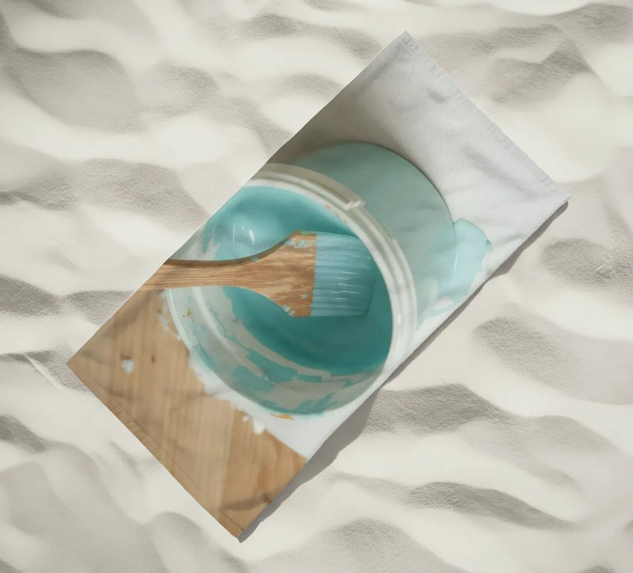 Il pennello di legno è appoggiato in un barattolo di vernice blu accanto a un pennello piccolo. telo mare da DesignDoodle