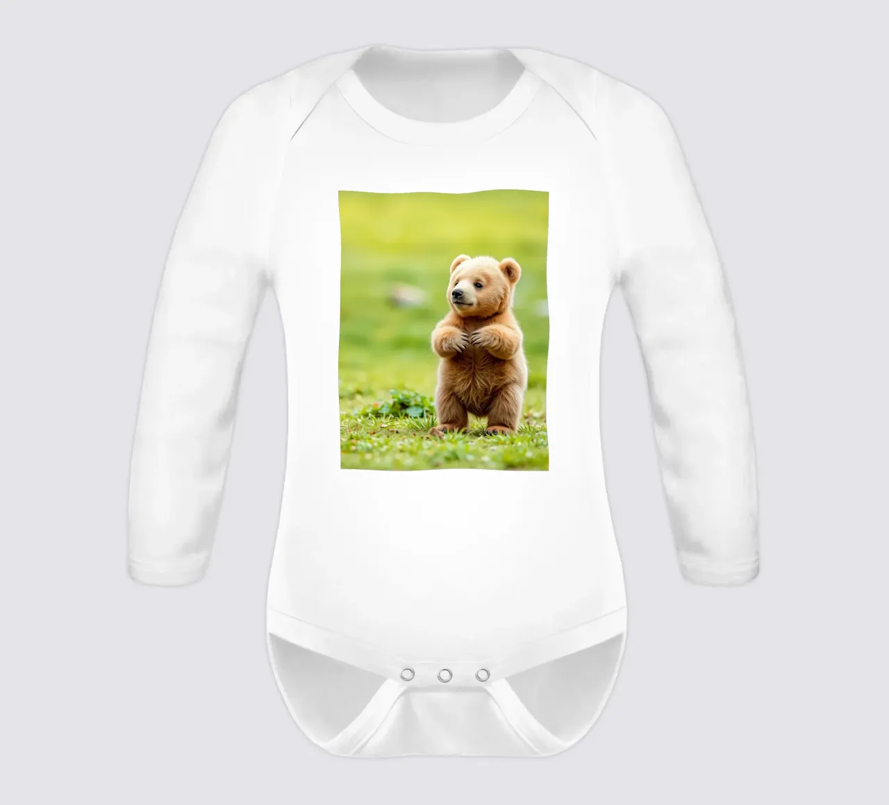 Un tenero cucciolo di orso bruno si regge su due zampe in un campo verde e rigoglioso body neonato maniche lunghe da DesignDoodle
