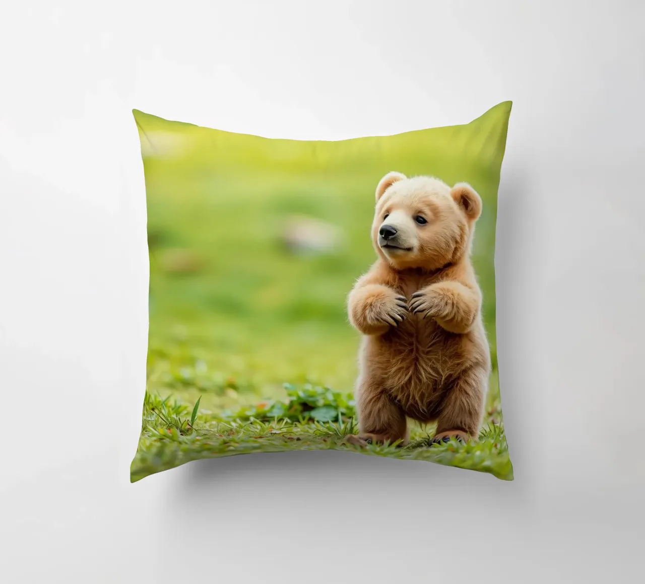 Un tenero cucciolo di orso bruno si regge su due zampe in un campo verde e rigoglioso cuscino da DesignDoodle
