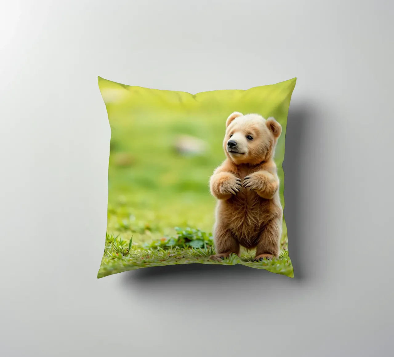 Un tenero cucciolo di orso bruno si regge su due zampe in un campo verde e rigoglioso cuscino da DesignDoodle