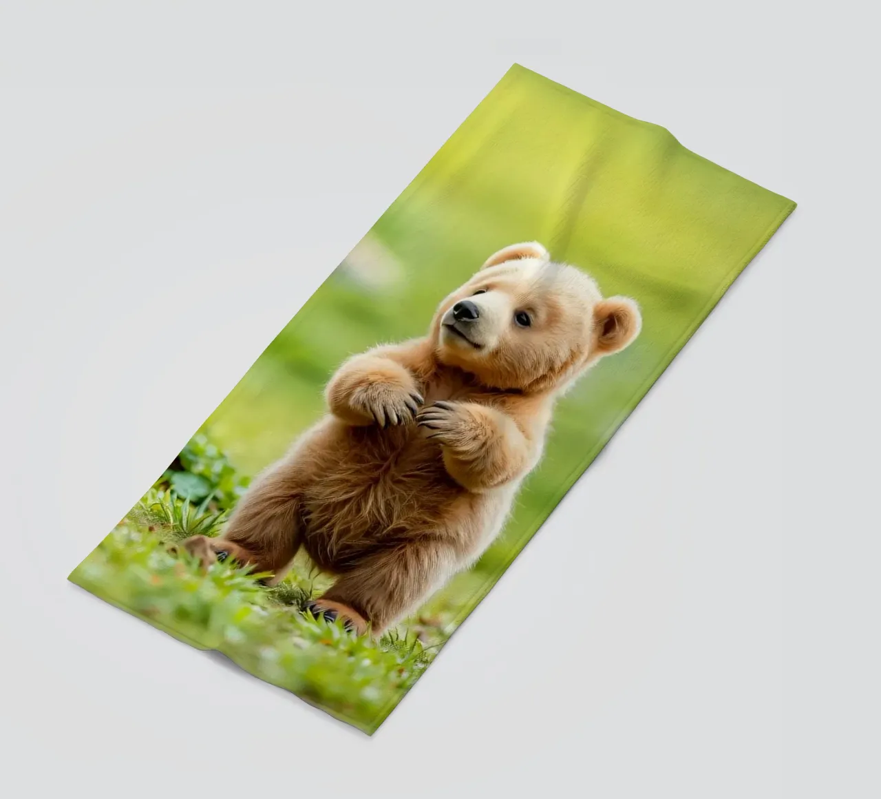 Un tenero cucciolo di orso bruno si regge su due zampe in un campo verde e rigoglioso telo mare da DesignDoodle