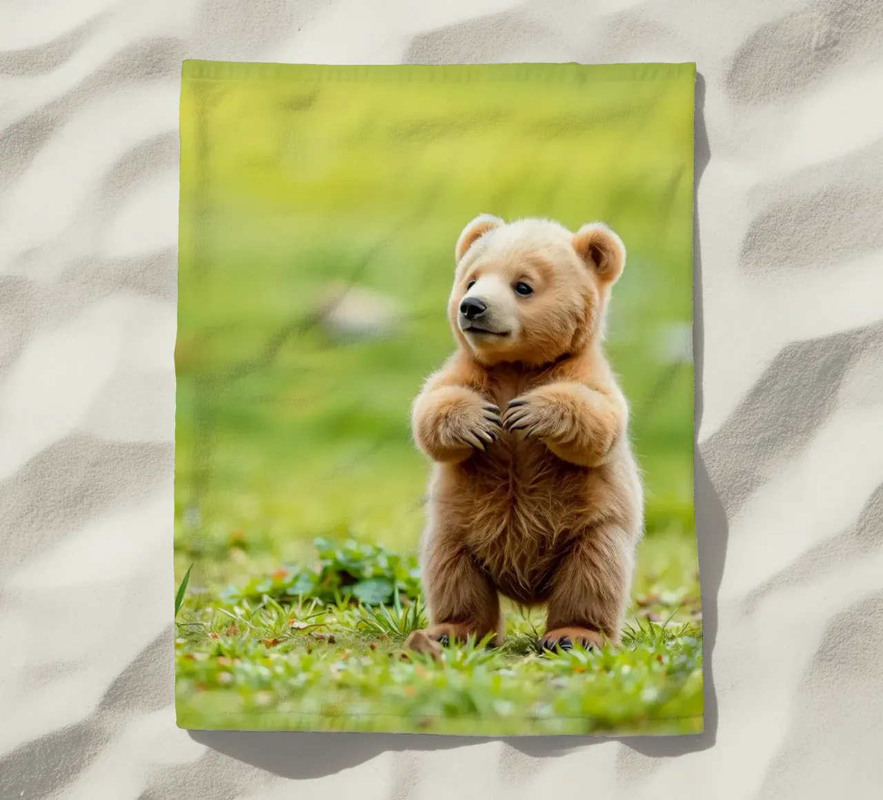Un tenero cucciolo di orso bruno si regge su due zampe in un campo verde e rigoglioso telo mare da DesignDoodle
