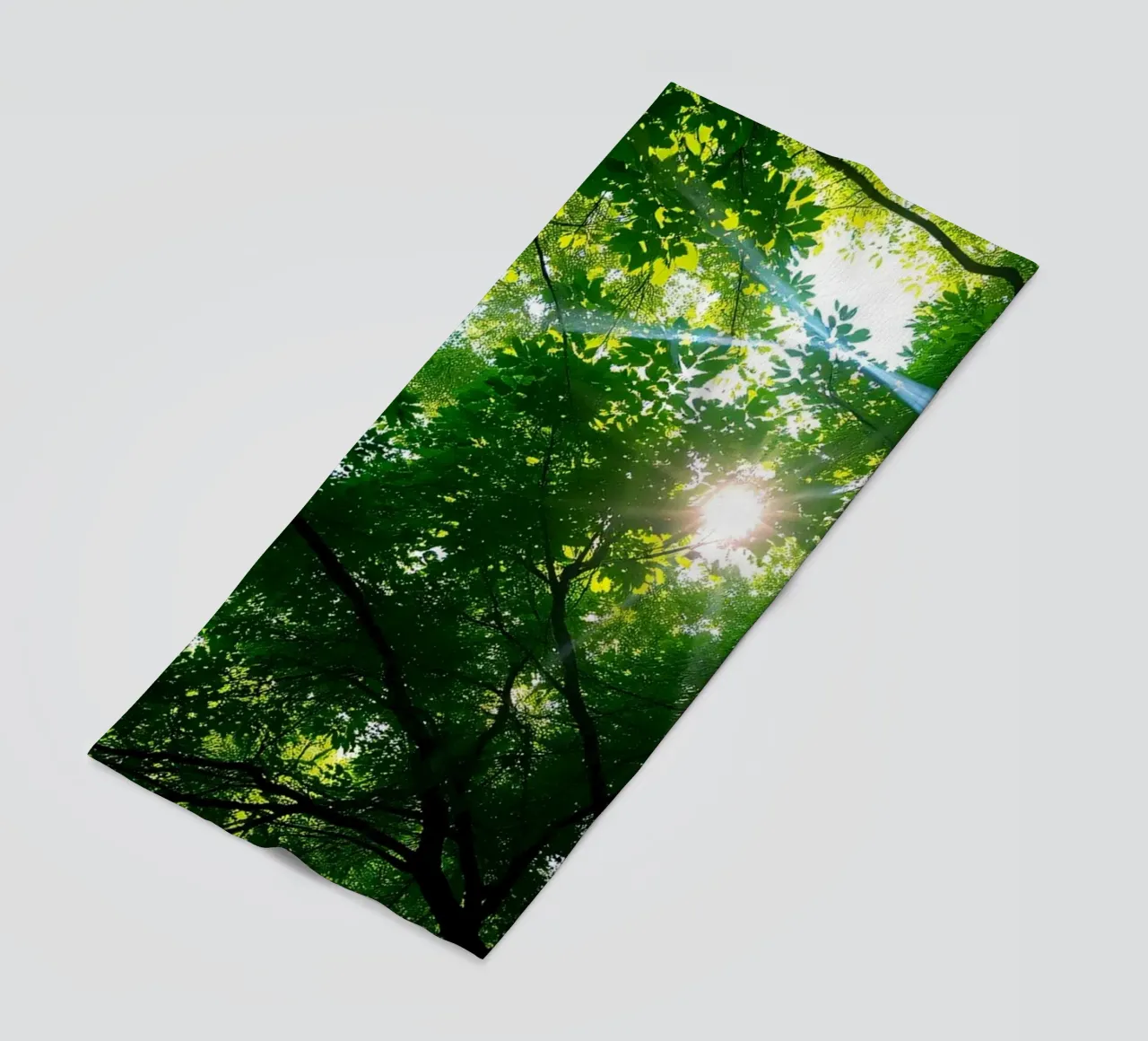 Sunlight filtering through dense green trees in calm beach towel by DesignDoodle