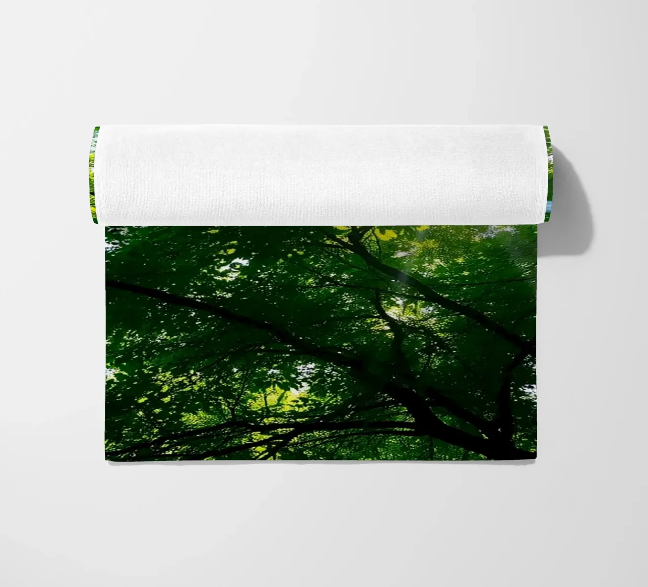 Sunlight filtering through dense green trees in calm beach towel by DesignDoodle