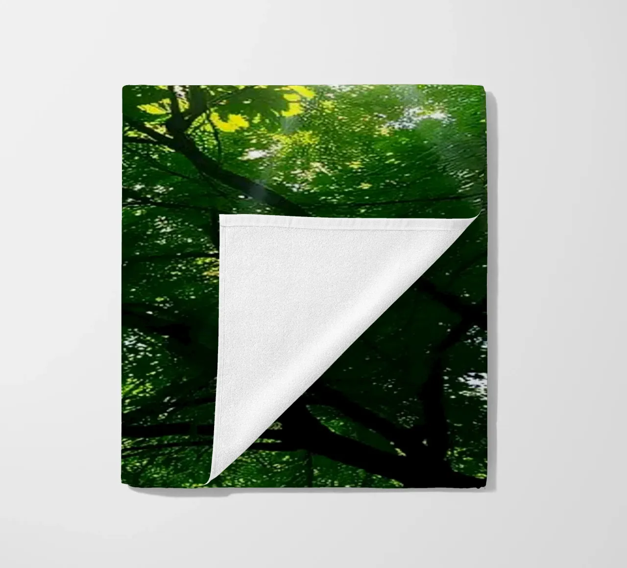 Sunlight filtering through dense green trees in calm beach towel by DesignDoodle