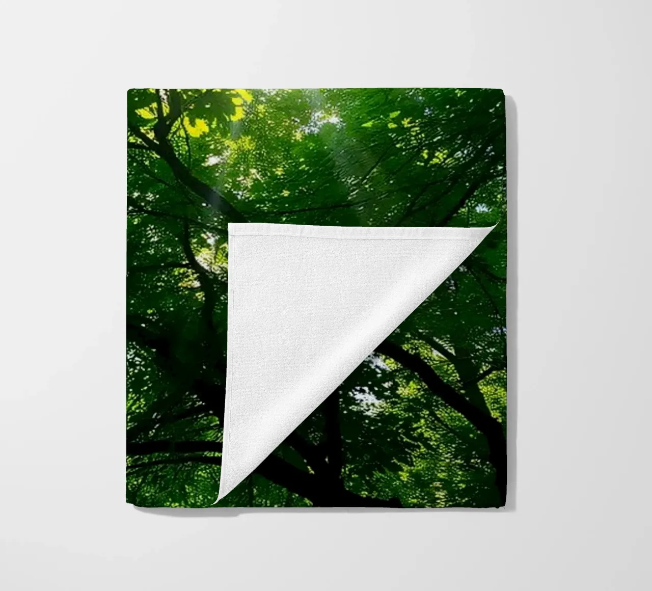 Sunlight filtering through dense green trees in calm beach towel by DesignDoodle