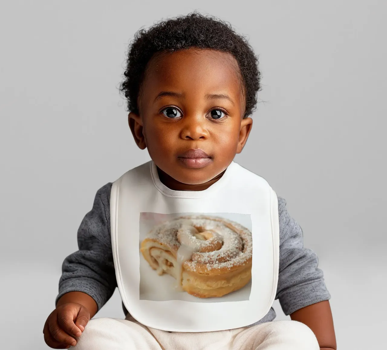 Warm cinnamon roll with cream icing and powdered sugar on a baby bib by DesignDoodle