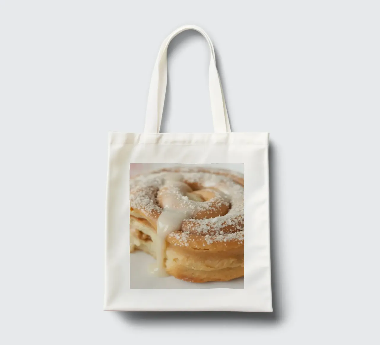 Warm cinnamon roll with cream icing and powdered sugar on a tote bag by DesignDoodle
