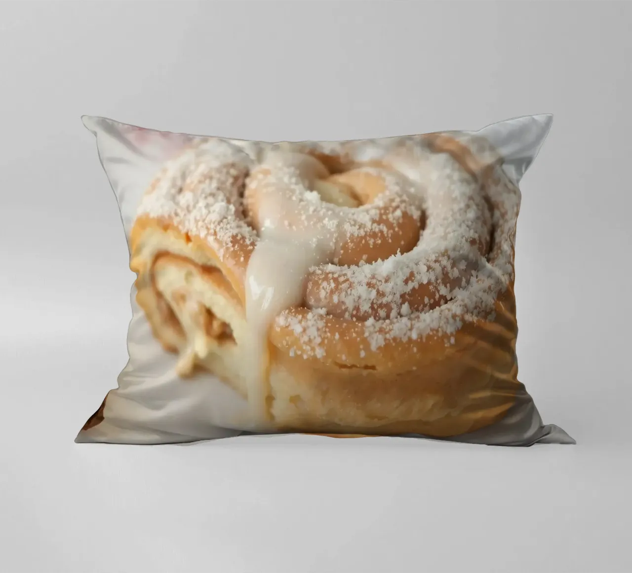 Warm cinnamon roll with cream icing and powdered sugar on a decorative cushion by DesignDoodle