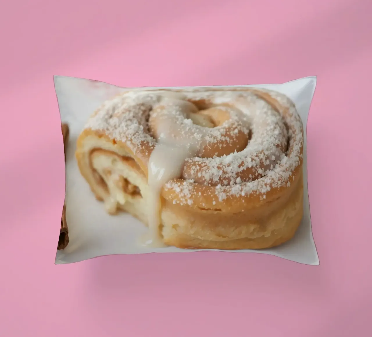Warm cinnamon roll with cream icing and powdered sugar on a decorative cushion by DesignDoodle