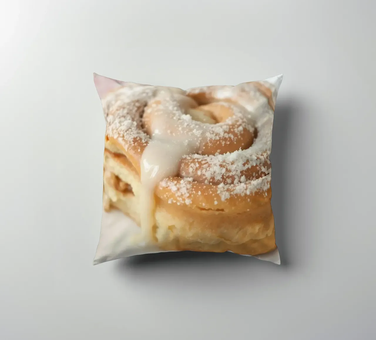 Warm cinnamon roll with cream icing and powdered sugar on a decorative cushion by DesignDoodle