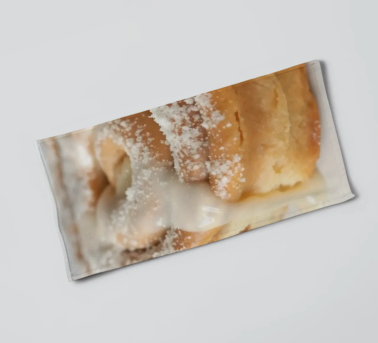 Rouleau chaud à la cannelle avec glaçage à la crème et sucre en poudre sur une plaque de cuisson. serviette de bain de DesignDoodle