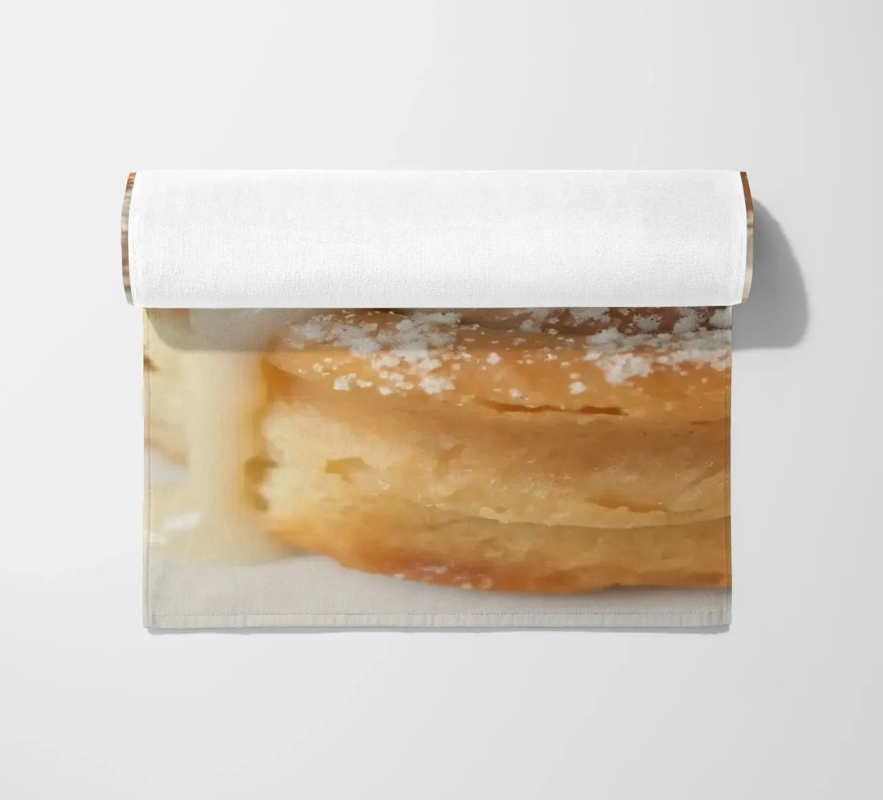 Warm cinnamon roll with cream icing and powdered sugar on a beach towel by DesignDoodle
