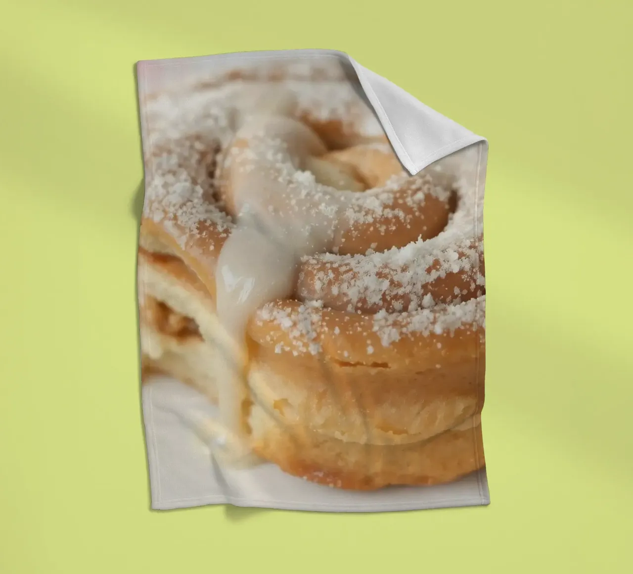 Warm cinnamon roll with cream icing and powdered sugar on a fleece blanket by DesignDoodle
