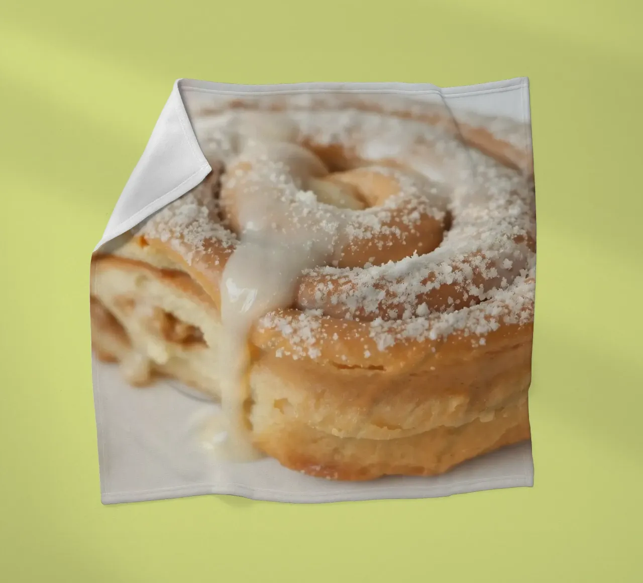 Warm cinnamon roll with cream icing and powdered sugar on a fleece blanket by DesignDoodle