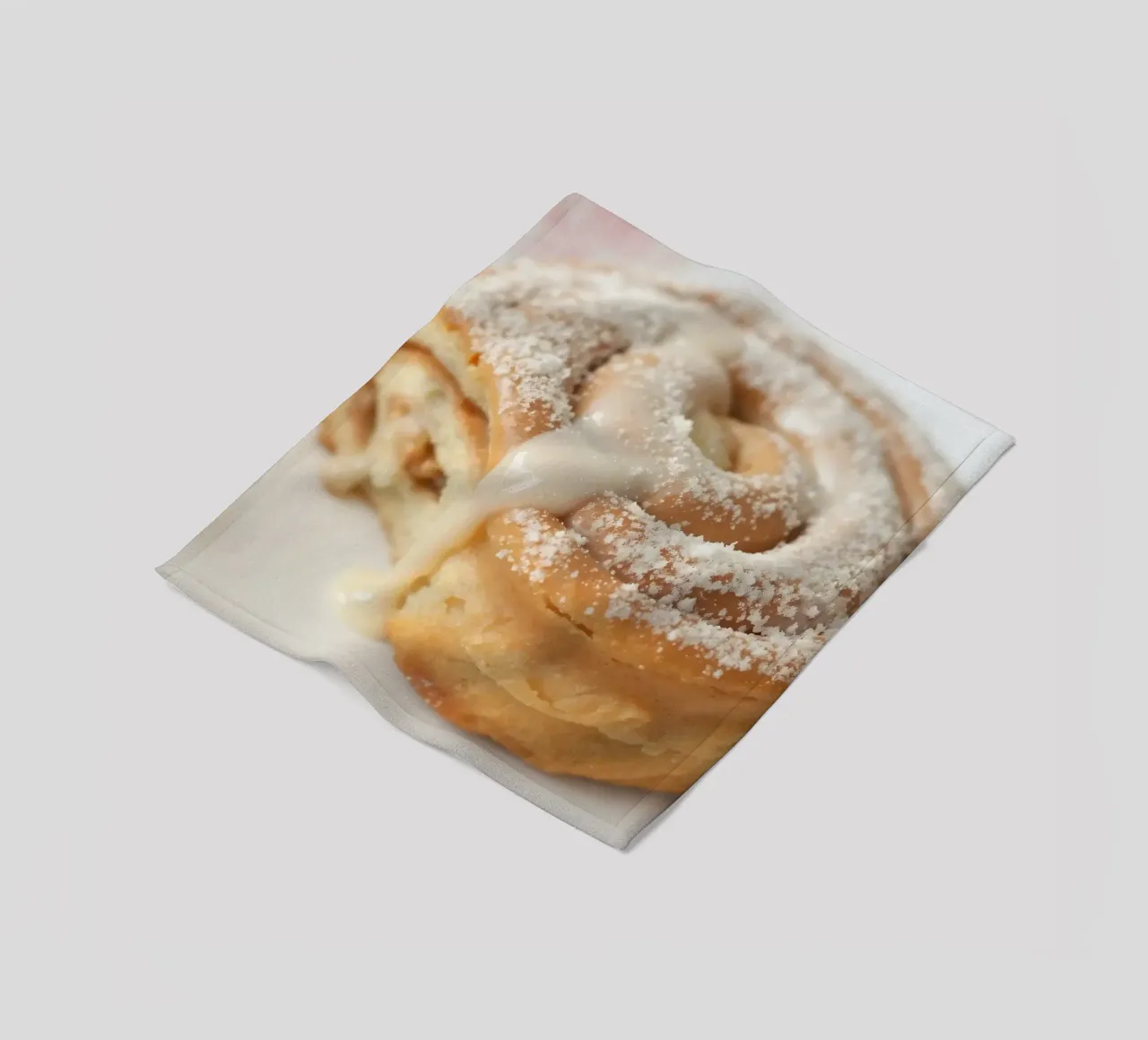 Warm cinnamon roll with cream icing and powdered sugar on a fleece blanket by DesignDoodle