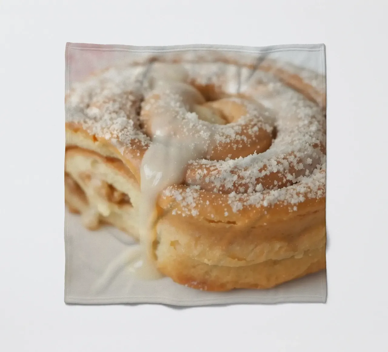 Warm cinnamon roll with cream icing and powdered sugar on a fleece blanket by DesignDoodle